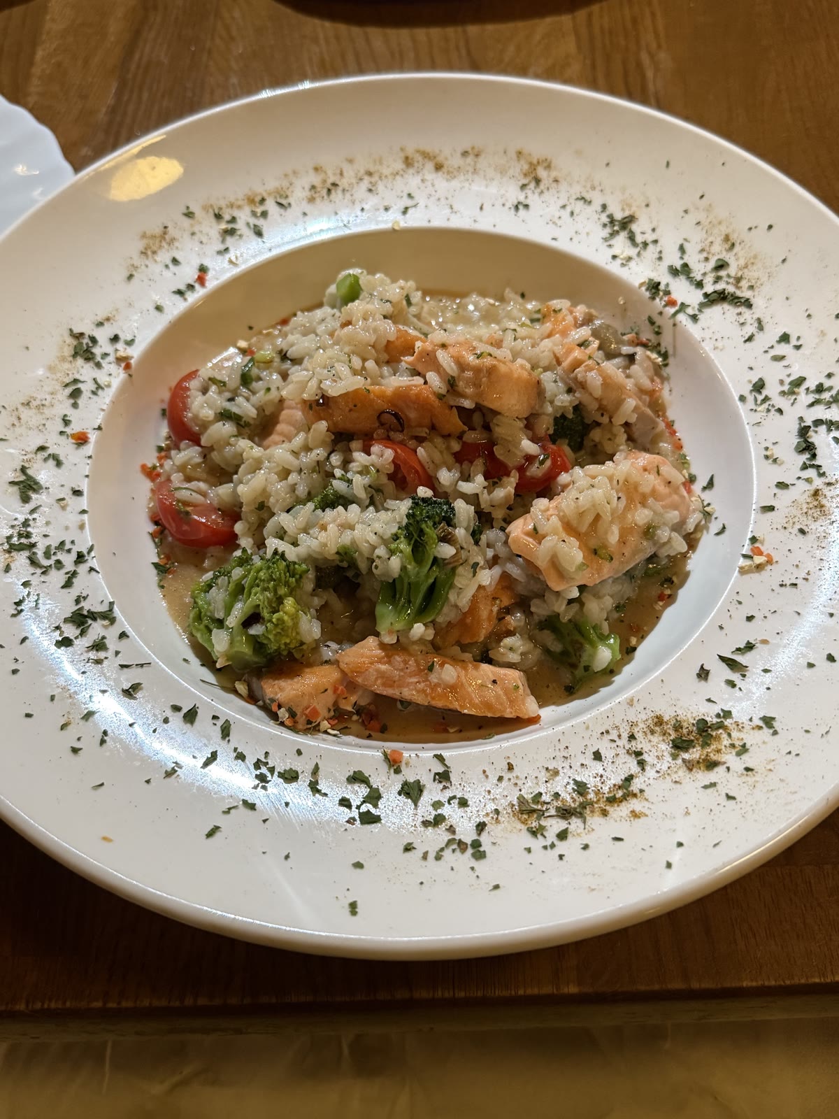 Risotto mit Lachs, Broccoli und Kirschtomaten auf einem tiefen Teller