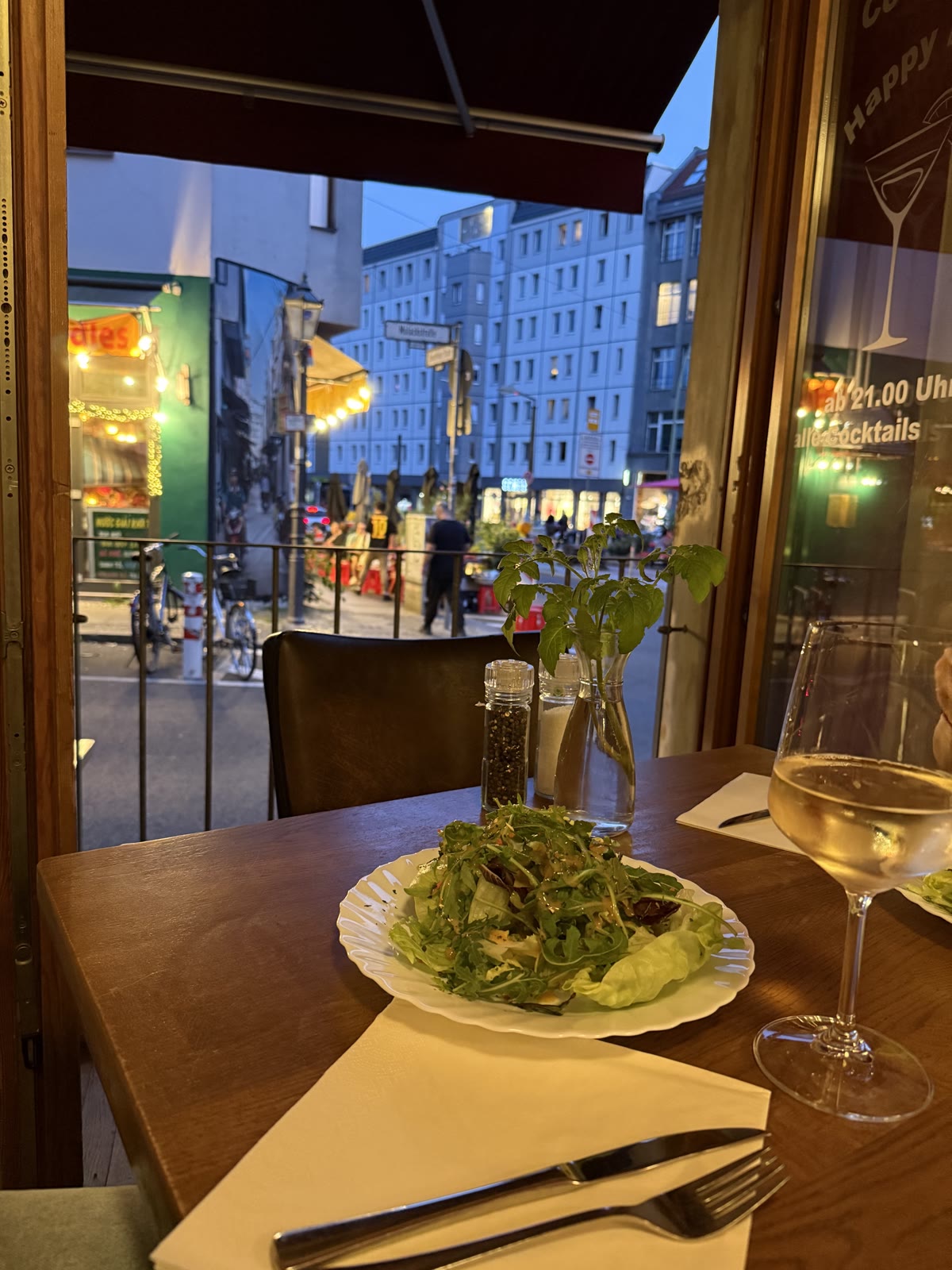 Tisch am Fenster mit Salat und Weißwein am Abend